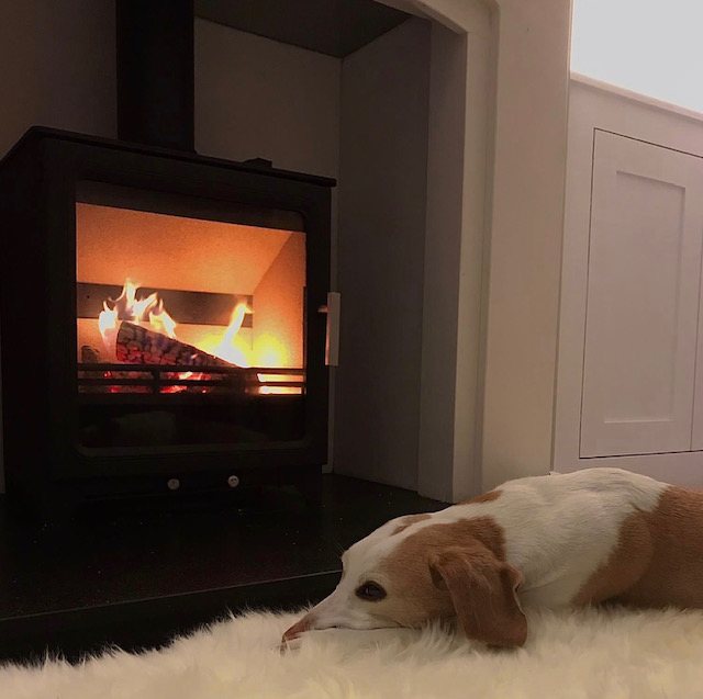 An ACR Woodpecker 5 Plus multi-fuel stove with a natural limestone fireplace and black granite hearth in Menston