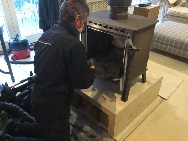 A chimney sweep power-sweeping a Stovax double-sided stove near Malton