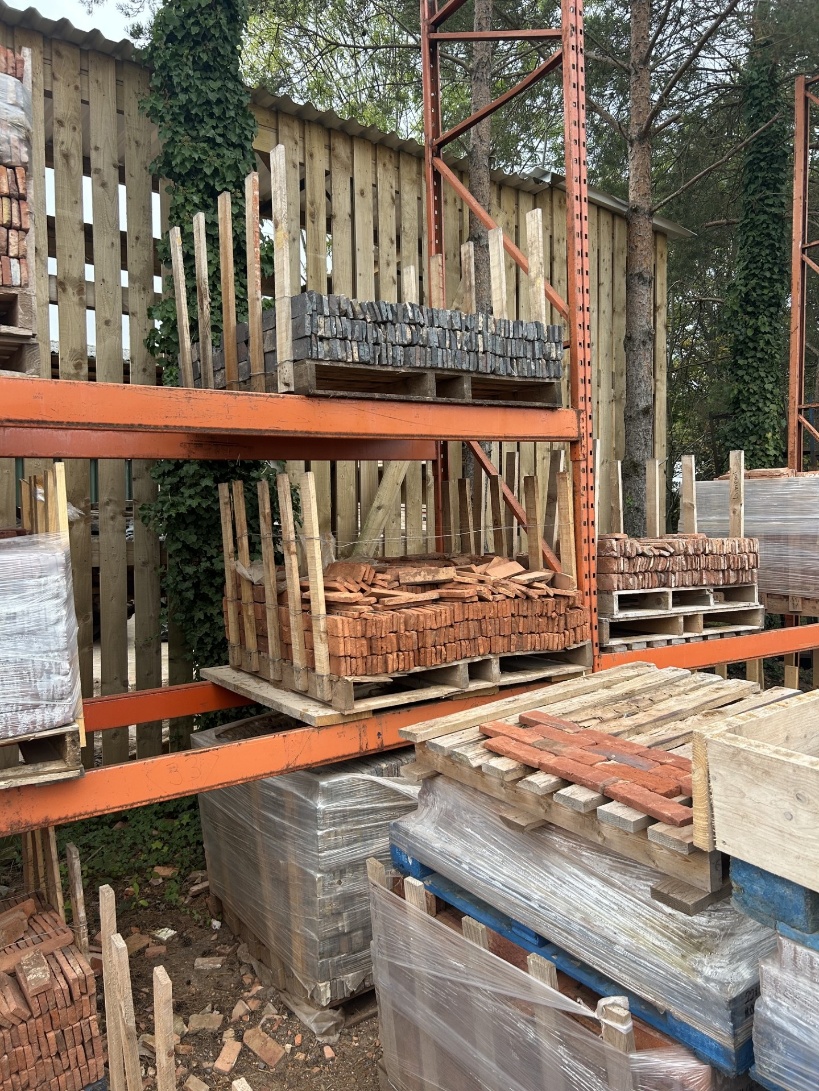 Reclaimed brick slips stacked in batches with individual bricks being laid out in the yard